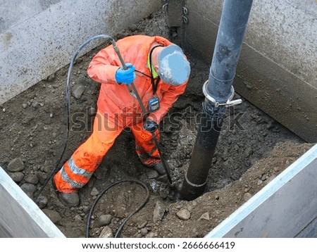 Construction worker using hydro vacuum to safely expose old watermain inside trench box during wet excavation.
