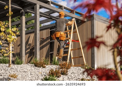 A construction worker is using a ladder to reach the top of a building under construction in a bright, sunny environment. Lush greenery surrounds the area.