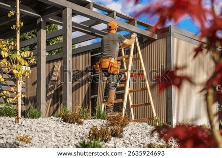 A construction worker is using a ladder to reach the top of a building under construction in a bright, sunny environment. Lush greenery surrounds the area.