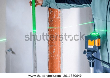 Construction worker using laser level and ruler taking measurements on site