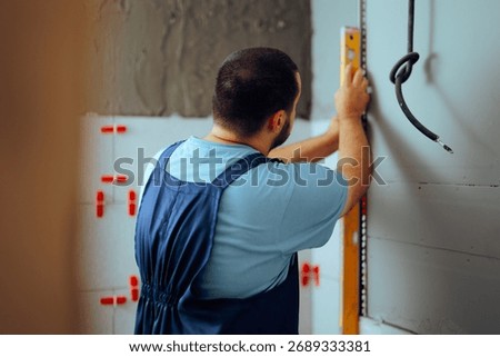 
Construction Worker Using a Leveling Straightedge for Tile Installation. Skilled constructor measuring for accurate installing faience tiles 
