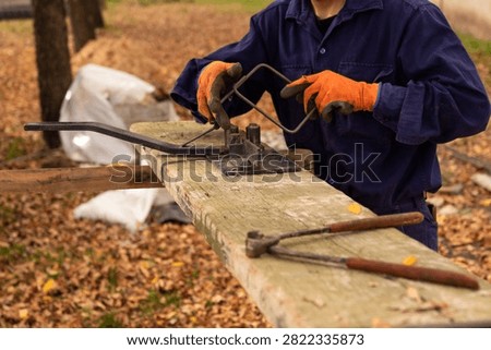 Construction worker using manual rebar bender to shape steel stirrups for concrete reinforcement
