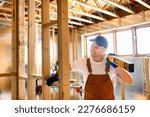 A Construction Worker Using Power Tool in Unfinished Basement of New Home