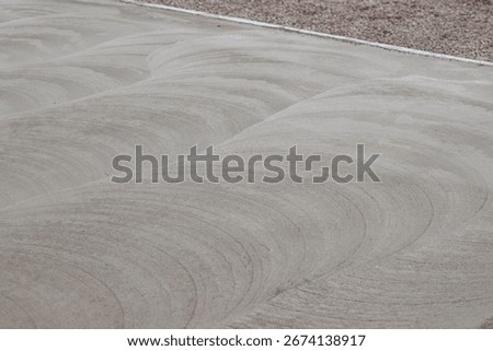 Construction worker using power trowel on concrete surface, Close-up of a construction worker operating a power trowel machine to smooth and finish freshly poured concrete on a building site.