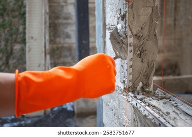Construction worker using a pvc corner bead to plaster a window corner.