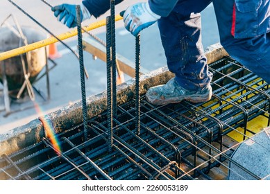 Construction worker using safety rules is working on a reinforced concrete slab preparing rebar or reinforncing bars
