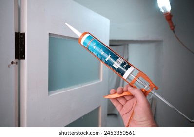 Construction worker using silicone sealant caulk. Accessories for assembling, install furniture, repair home. Man dressed in work attire, helmet and protective glasses. Caulk Sealant Application - Powered by Shutterstock