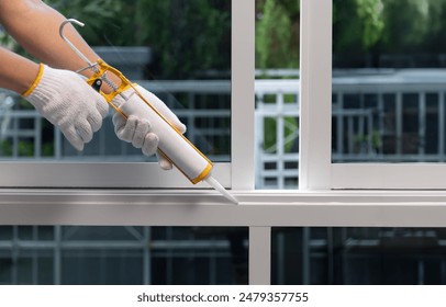 Construction worker using silicone sealant caulk for repair leaked inside window frame.
