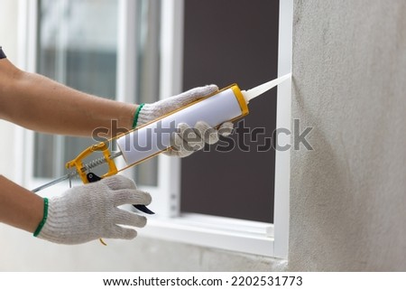 Construction worker using silicone sealant caulk the outside window frame.