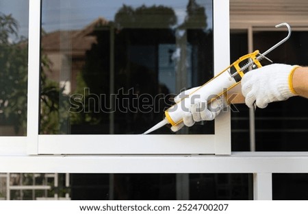 Construction worker using silicone sealant caulk for repair leaked inside window frame.