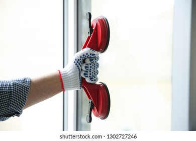 Construction worker using suction lifter during window installation indoors, closeup
