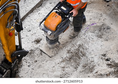 construction worker using a tamping compactor