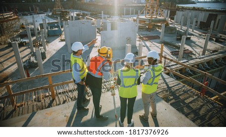 Construction Worker Using Theodolite Surveying Optical Instrument for Measuring Angles in Horizontal and Vertical Planes on Construction Site. Engineers and Architect Discuss Plans Next to Surveyor.