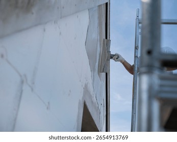 Construction worker using trowel to apply render or plaster to exterior wall during building renovation project