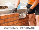 Construction Worker Using Trowel to Lay Brick Wall During Daytime