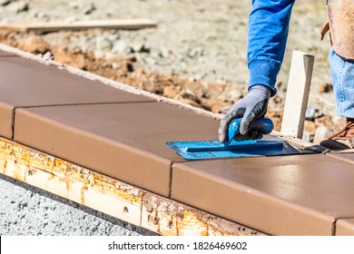 Construction Worker Using Trowel On Wet Cement Forming Coping Around New Pool.