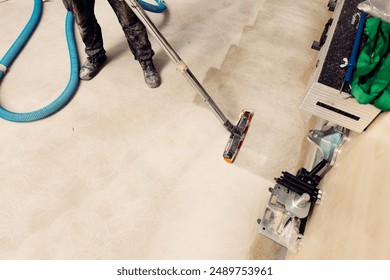 Construction worker using vacuum cleaner to remove dust during renovation work