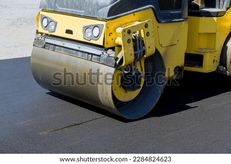 Construction worker in vibratory road roller compactor machine operator laying asphalt