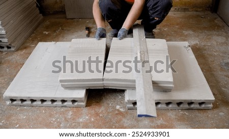 Construction worker wearing gloves assembling lightweight concrete blocks on a construction site using a level for precise alignment