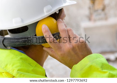 Construction worker wearing protective hard hat and ear defenders