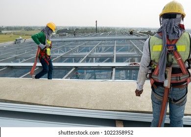 Construction Worker Wearing Safety Harness And Safety Line Working On A Metal Industry Roof New Warehouse