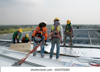 Construction Worker Wearing Safety Harness And Safety Line Working On A Metal Industry Roof New Warehouse