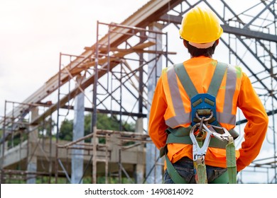 Construction worker wearing safety harness and safety line working at high place,Practices of occupational safety and health can use hazard controls and interventions to mitigate workplace hazards. - Shutterstock ID 1490814092