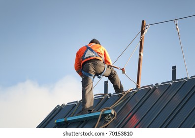 Construction Worker Wearing Safety Harness And Safety Line Working On A Pitched Roof