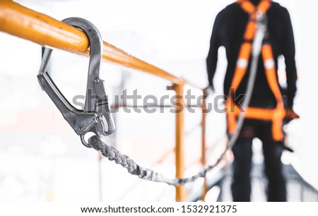 Construction worker wearing safety harness and safety line working at high place. Working at height equipment. Fall arrestor device for worker with hooks for safety body harness