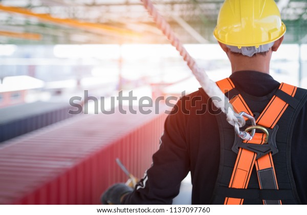 Construction worker wearing safety harness and\
safety line working at high\
place