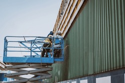 Construction Worker Wearing Safety Harnesses On Scissor Hydraulic Lift Or X-lift And Cutting Steel With Acetylene Torch At A Construction Site, Mobile Aerial Work Platform
