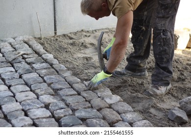 A construction worker who is laying cobblestones in cement, stone setters, path construction, paving stones