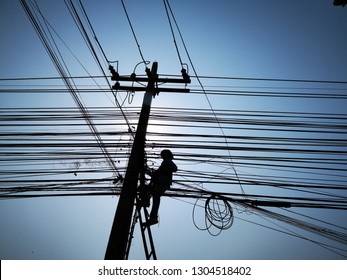 Construction Worker Is Wiring Cable At Electric Pole, Many Cable On Blue Sky Background.