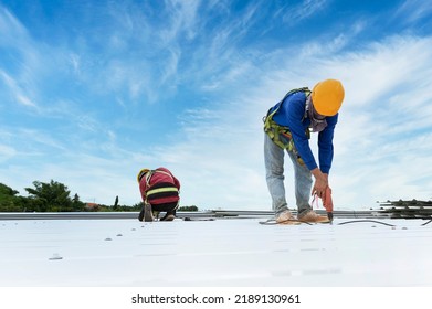 Construction worker in work clothes installing new roofing tools roofing tools, electric drill, and use on new wooden roofs with metal sheets. - Shutterstock ID 2189130961