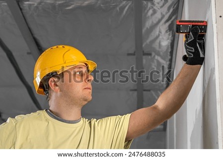 A construction worker is working with the laser distance meter.