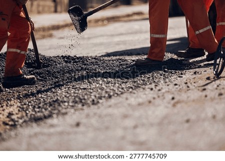 Construction worker working on a new asphalt layer on a public street.