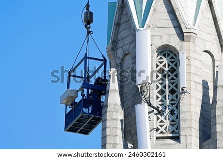 The construction worker is working on the top of the church on the background of blue sky