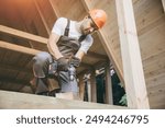 Construction worker working with screwdriver on wooden frame, diy eco-friendly homes concept. Man using drill working on construction of wood modular house