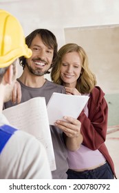 Construction worker young couple holding paper smiling