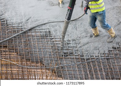 construction workers apply fresh concrete to the reinforcement with a concrete pump