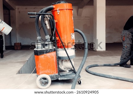 Construction workers applying epoxy coating on concrete floor and using industrial vacuum cleaner