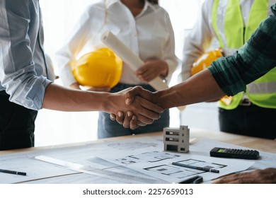 Construction workers, architects and engineers shake hands after completing an agreement in an office facility, successful cooperation concept. - Powered by Shutterstock