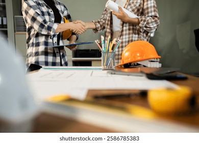 Construction workers, architects and engineers shake hands while working for teamwork and cooperation after completing an agreement in an office facility, successful cooperation concept.