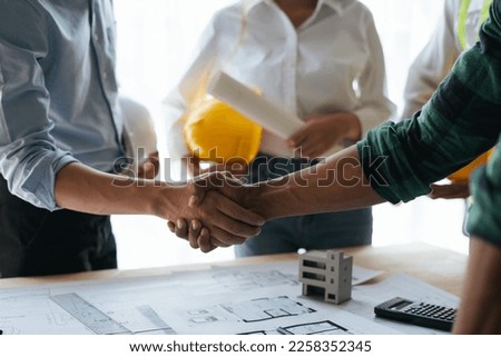 Construction workers, architects and engineers shake hands after completing an agreement in an office facility, successful cooperation concept.