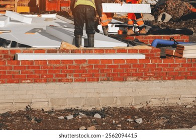 Construction workers assembling Insulation polystyrene on a building site in broad daylight amidst ongoing development efforts - Powered by Shutterstock