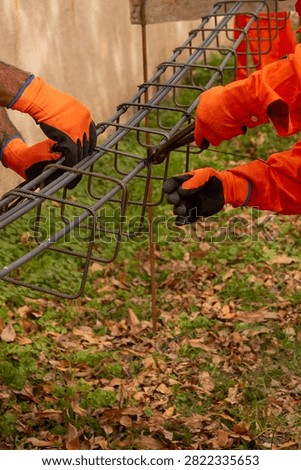 Construction workers assembling and tying steel rebar cage with stirrups for concrete beam