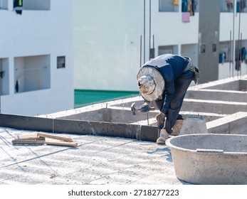 Construction workers assembling wooden formwork for concrete foundation on site.
