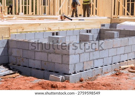 Construction workers build block wall foundation for new house in residential area