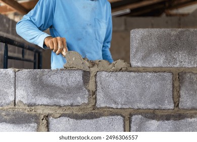 Construction workers are building cement walls with brick blocks. - Powered by Shutterstock