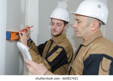 construction workers checking the level on the wall indoors